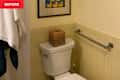Bathroom corner featuring a white toilet with a woven basket on top, yellow tiled walls, and a towel hanging nearby.