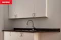 A kitchen area featuring white cabinets, a dark countertop, and a modern faucet above a double sink.