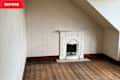 Empty room with wooden floor, white decorative fireplace, and textured wallpaper.