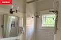 Bathroom with white subway tile, a large mirror, a showerhead, and a window with greenery outside.