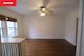 Empty room with hardwood floors, ceiling fan, and two windows with bamboo shades.