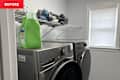 Washer and dryer in a laundry room with a green detergent bottle and neatly stacked towels on a shelf.
