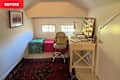 Home office corner with a white desk, swivel chair, colorful storage boxes, and a bulletin board filled with notes.