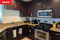 Modern kitchen with dark wood cabinets, stainless steel appliances, granite countertops, and a double sink.