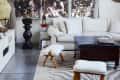 Living room with white sofa, zebra-patterned rug, large windows, and a circular chandelier.
