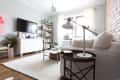 Living room with white sofa, brick wall, TV, bookshelf, and modern lamp on side table.