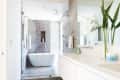 A bathroom with large glass doors in front of a walk-in shower and tub.