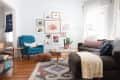 Living room with a teal armchair, gray sofa, colorful cushions, gallery wall, and patterned rug.