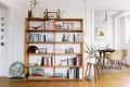 A wooden bookshelf is in a living room with white walls