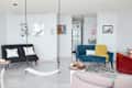 Living room with a black futon, blue sofa, yellow throw, wall art, and a swing. Modern decor with a zigzag rug and coffee table.