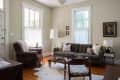Living room with a brown leather armchair, gray sofa, white floor lamp, and framed portrait on the wall.
