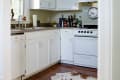 Cozy kitchen with white cabinets, a gas stove, a cowhide rug, and a wall clock above the counter.