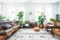 Bright living room with mid-century sofa, patterned cushions, large plants, wooden furniture, and a geometric rug.