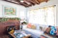 Cozy living room with white sofa, colorful pillows, brick fireplace, and vibrant artwork above mantel.