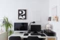 Home office with dual monitors, black desk lamp, potted plant, and wall art featuring a large number two.