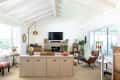 Living room with vaulted ceiling, TV above stone fireplace, globe, books, plants, and a brown leather lounge chair.