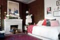 Cozy living room with brick walls, white fireplace, colorful abstract art, and a daybed with pink and gray pillows.