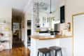A neutral kitchen with a hanging basket for fruit over the counter