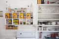 Kitchen shelves with vintage tins, glass jars, spices, and dishes above a white stove.