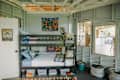 Bunk bed with colorful bedding, a wall tapestry, and toys in a cozy, light-filled room.