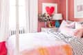 Pink bedroom with lots of light and heart art on the wall