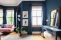 Living room with pink sofa, blue walls, large mirror, potted plant, and abstract art near a window with blue curtains.