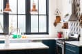 a moody kitchen with white countertops and copper light fixtures