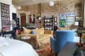 Loft-style living room with exposed brick, beige sofas, blue armchair, colorful artwork, and a decorative rug.