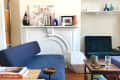 Living room with blue sofas, white fireplace, abstract art, and decorative vases on the mantel.