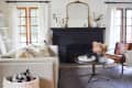 Living room with beige sofa, black fireplace, round coffee table, and leather chair, featuring floral arrangement and decor.