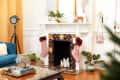 Living room with a decorated fireplace, pink stockings, plants, and a blue sofa.