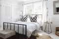 Wrought iron bed in white bedroom in front of window
