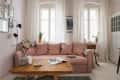 Cozy living room with a pink sofa, wooden coffee table, plants, and framed art on the wall.