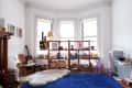 Living room with a blue rug, wooden shelves filled with books and toys, a guitar, and a play kitchen set.