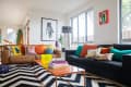 Living room with brown and black sofas, colorful pillows, zigzag rug, and modern art on walls.