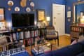 Cozy living room with blue walls, bookshelves, a TV, patterned chairs, and decorative plates on the wall.