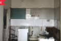 Unfinished kitchen with exposed wiring, a washing machine, and partially tiled walls.