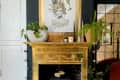 An ornate gold fireplace frame against a navy blue wall; a small portable fireplace sits inside the frame