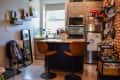A small kitchen with a short island and bar chairs