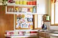Retro kitchen with wooden cabinets, colorful canisters, a plant, and a bulletin board with children's artwork.