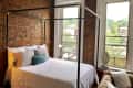 Sleeping area with sleek black metal bed frame and exposed brick walls