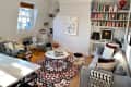 Cozy living room with a gray sofa, patterned rug, bookshelves, and modern art on the walls.