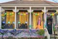 House decorated for Mardi Gras with colorful balloons, gold curtains, and festive cutouts on the porch.
