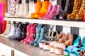 Colorful and eclectic collection of boots and high heels on display shelves, featuring glitter, spikes, and animal prints.