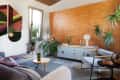 Modern living room with geometric wall art, wooden accent wall, plants, and a light blue sideboard with decor items.