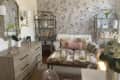 Living area with loveseat, two selves, floral wallpaper, dresser, and large mirror