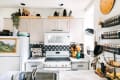 Cozy kitchen with white cabinets, black and white backsplash, espresso machine, spice racks, and decorative shelves.