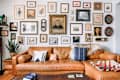 Brown leather sectional sofa with patterned pillows, a throw, and a gallery wall of framed art and photos above.