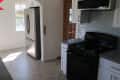 Modern kitchen with stainless steel fridge, black stove, gray countertops, and white cabinets, labeled "Before."