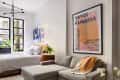Modern bedroom with a gray sectional sofa, large art print, and a bed by the window with plants and abstract wall art.